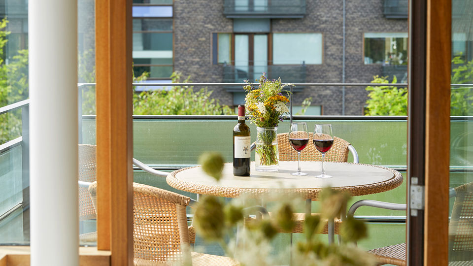 Hotellejlighed med solrig altan og vin på bordet