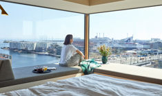 Kvinde kigger ud af vindue med udsigt over havnen i 50 m2 hotellejlighed