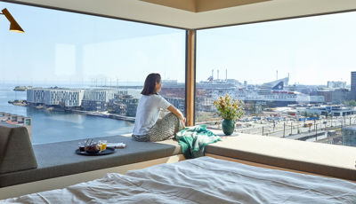 Kvinde kigger ud af vindue med udsigt over havnen i 50 m2 hotellejlighed