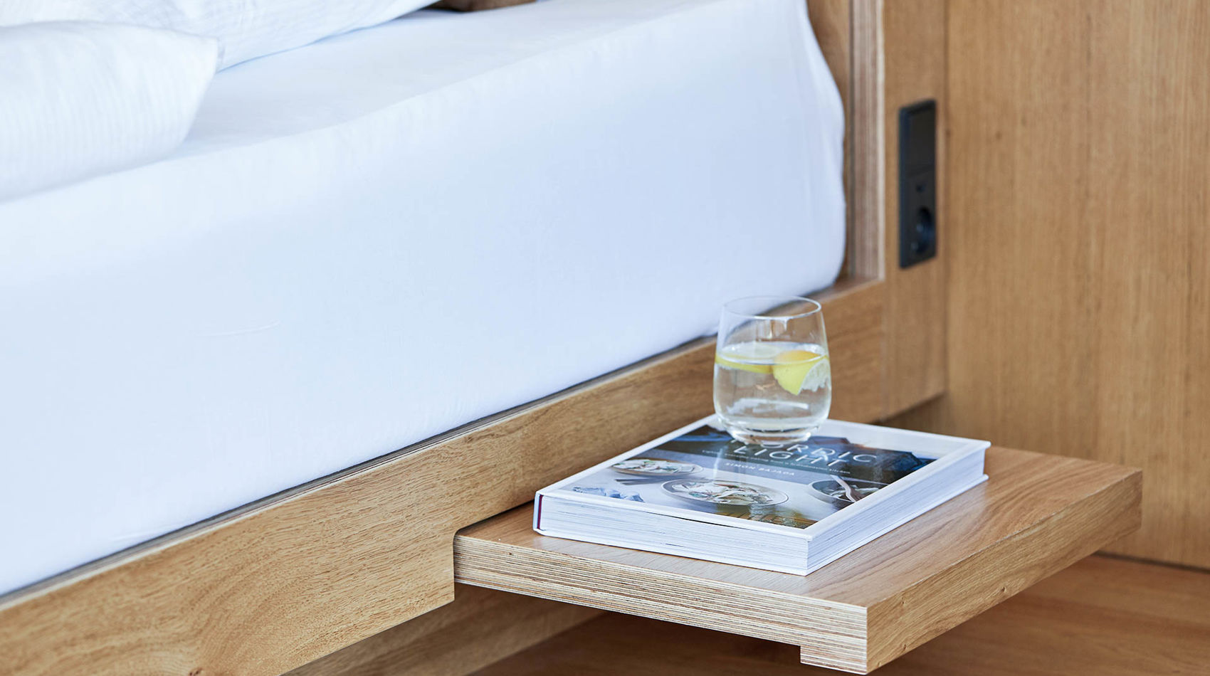 Seng med indbygget sengebord med bog og vandglas på i 70 m2 hotellejlighed